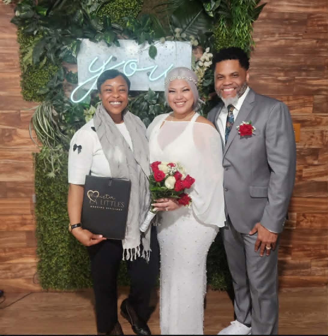 Minister La Littles with newlyweds at neon sign backdrop